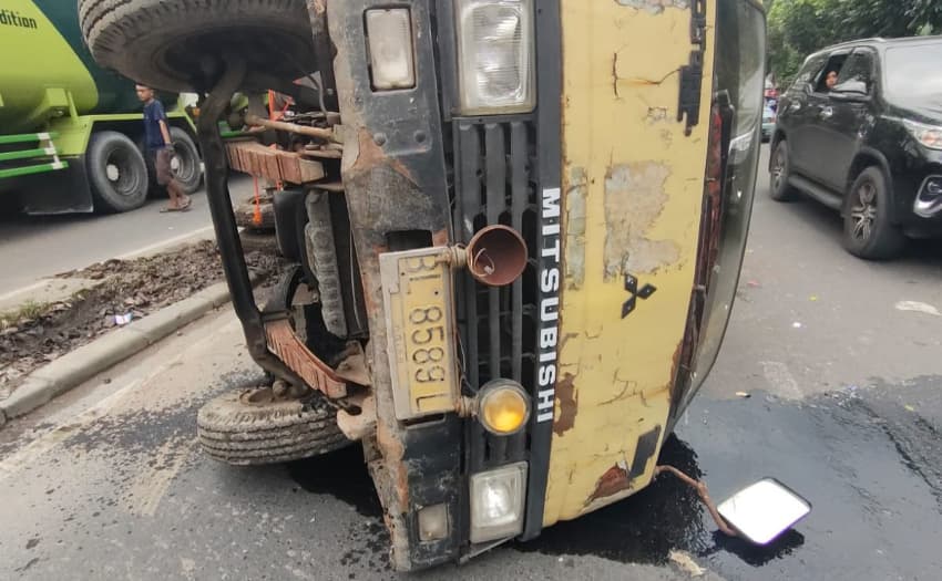 hantam_pembatas_jalan_truk_muatan_barang_bekas_terbalik_di_sunggal
