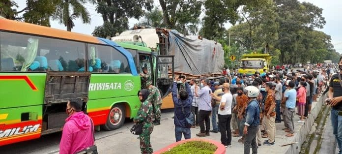 bus_pariwisata_dan_truk_pengangkut_kayu_laga_kambing_depan_korem