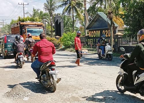 pak_ogah_beraksi_di_jalan_rusak_depan_kodim_deli_serdang_rupiah_pengendara_diminta